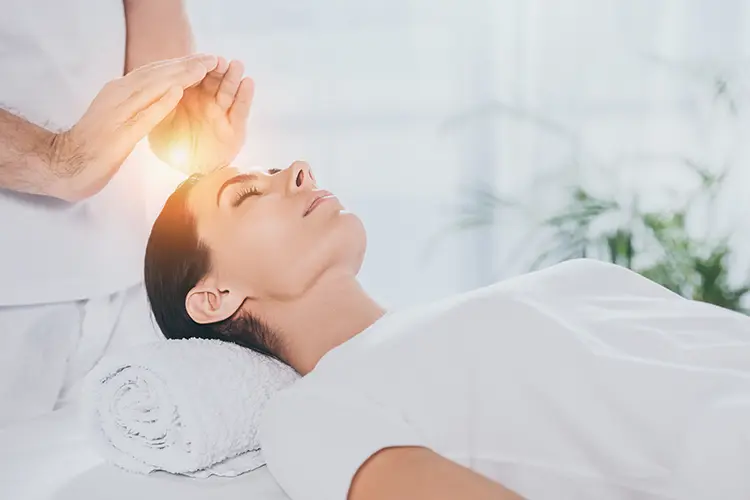 A reiki practitioner holding their hands gently near a client during a session