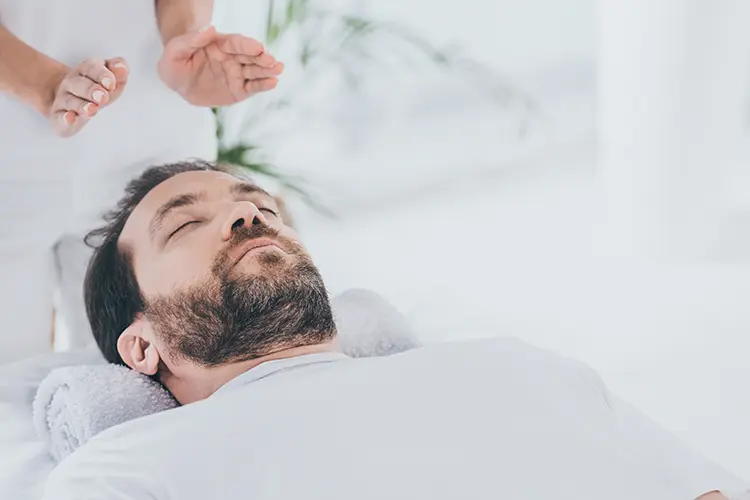 A reiki practitioner's hands positioned gently above a client during a session