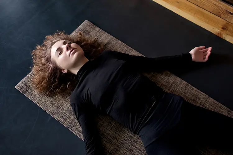 A person resting in a relaxed, restorative pose during yoga nidra